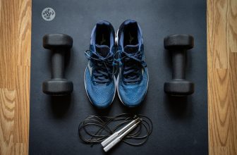 A collection of various fitness gear including dumbbells, yoga mats, and resistance bands arranged in a home setting.