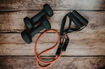 A collection of simple workout accessories like resistance bands, yoga mats, and dumbbells arranged in a cozy home setting.